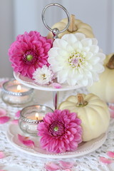 Obraz na płótnie Canvas dahlias, pumpkins and candle on tiered cake stand as decoration