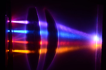 Light beams in colorblind-friendly colors pass trough a demonstration lens, the influence on the beams can be seen on the screen