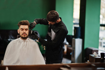 Handsome bearded man at the barbershop, barber at work.