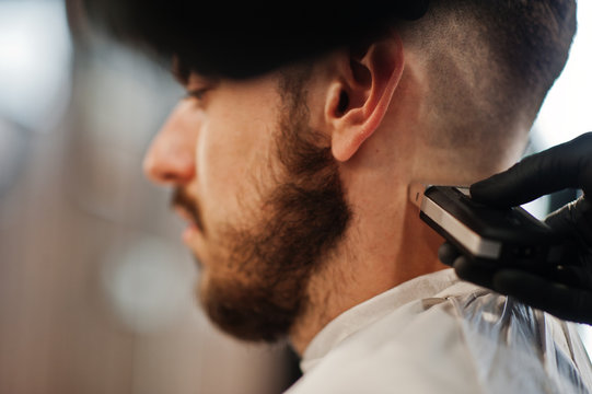 Handsome bearded man at the barbershop, barber at work. Close up nape.