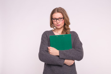 Young student woman in black glasses posing with green folder on white background