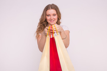 People, sale and consumerism concept - Beautiful woman over white background holding shopping bags