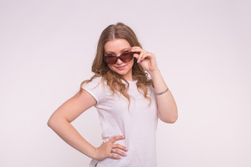 Portrait of enigmatic beautiful white girl fixing hair wearing sunglasses on white background