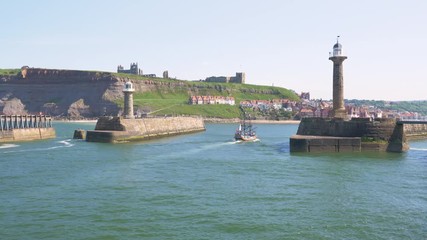 A pirate ship pleasure boat full of tourists returns to Whitby harbour.