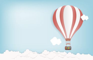 Fototapeta premium Hot air balloon in the sky with clouds and snowing. Origami paper art and digital craft style. Vector illustration