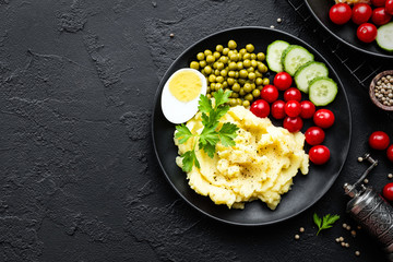 Mashed potato with green peas, tomatoes and boiled egg. Potato puree on plate with vegetables and egg