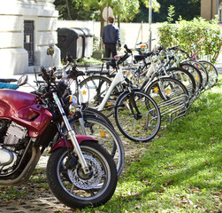 Fototapeta na wymiar Eine Person geht zu Fuß an einem Motorrad und zahlreichen Fahrrädern vorbei