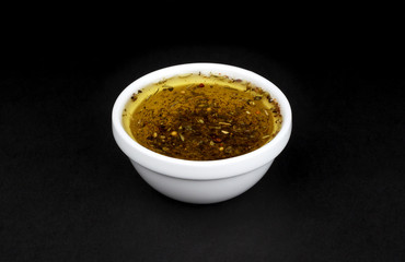 Oil salad dressing in white bowl isolated on black background