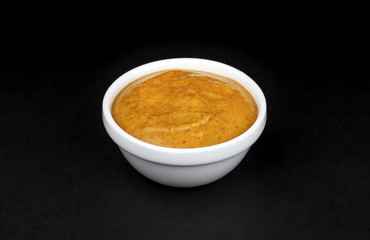 Mustard in white bowl isolated