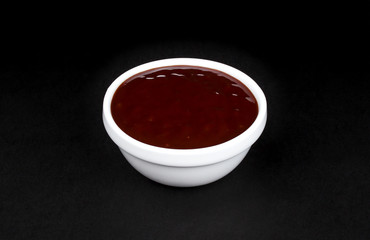 Barbecue sauce in white bowl on black background