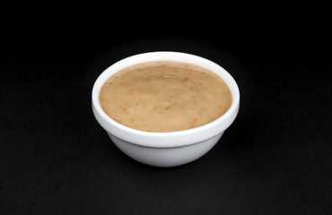 Peanut sauce. Tahini in bowl isolated on black background