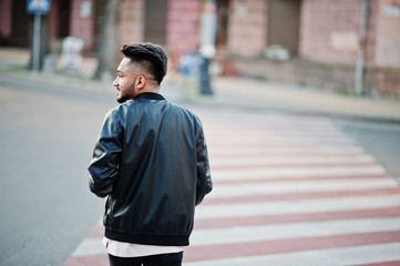 Stylish indian beard man at black leather jacket walking on zebra crossing. India model posed outdoor at streets of city.