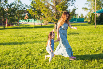 Fototapeta premium Family and child concept - Mother and daughter walking in the park and enjoying the beautiful nature.