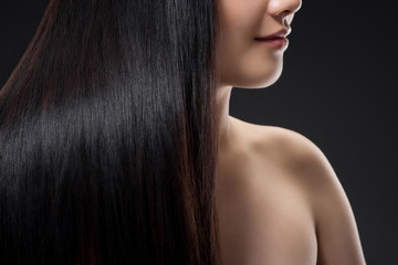partial view of smiling woman with shiny healthy and strong hair isolated on black