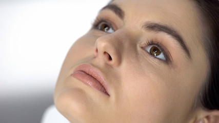 Young lady face with nude makeup closeup, cosmetic procedures, eyesight check