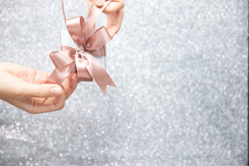 Female hands holding or pulling ribbons of a small gift box