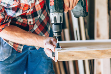 carpenter working with a drill on a wooden table