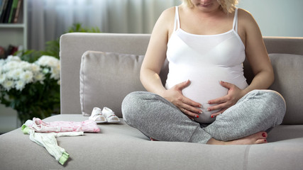 Happy pregnant woman massaging her belly, calming and relaxing fetus inside