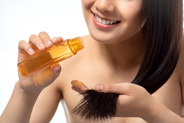 Fototapeta premium cropped shot of smiling woman pouring oil on split ends isolated on white