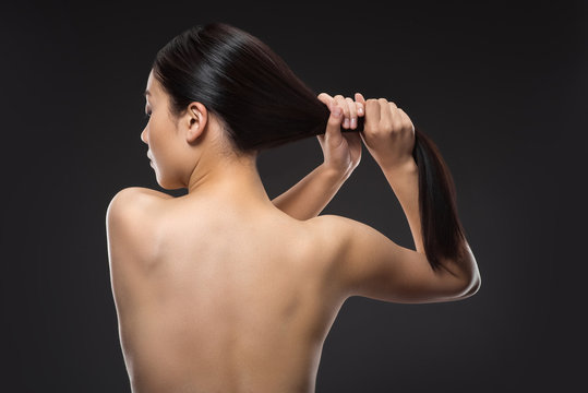 back view of shirtless woman with beautiful shiny hair isolated on black