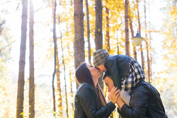 Fototapeta na wymiar Parenthood, fall and people concept - young family happy in autumn park