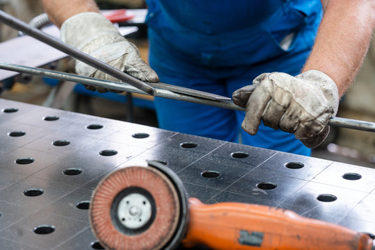 Worker in factory deburring workpieces of metal, close-up on hands