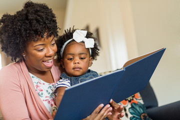 Mother reading a book to her little girl.