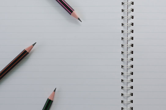 Wirebound Notebook Open with Lined Paper and Pencils.