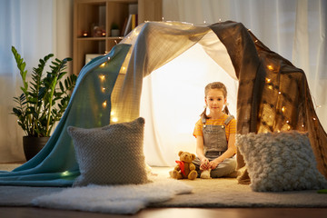 childhood and hygge concept - happy little girl with toys in kids tent at home © Syda Productions