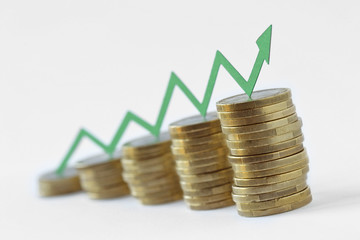 Piles of coins with green raising arrow - Money growth concept