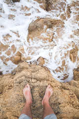 Top view of male bare feet on coastal rocks