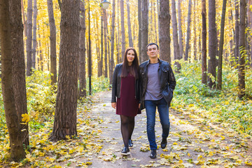 Couple in love holding hands and walking through a park on a sunny autumn day
