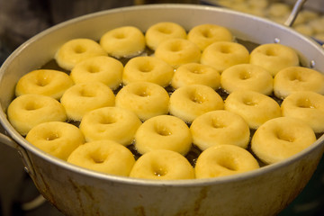 Frying donuts in oiled pans.