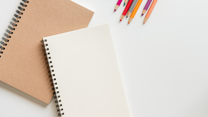 open blank spiral notebook with pencil, eraser and color pencil on white background.