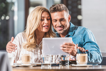 girlfriend and boyfriend using tablet at table in cafe