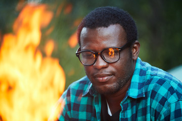 Young man looking at campfire while having rest in the forest during backpack trip