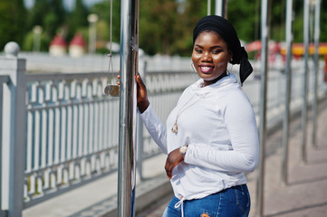 African muslim girl in black hijab, white sweatshirt and jeans posed outdoor.