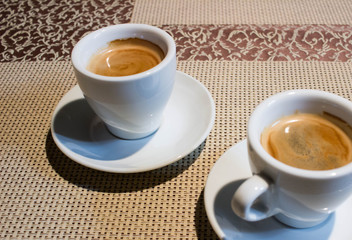 Two coffee cups, white serving plates, small metal spoons
