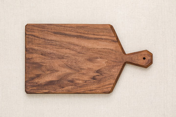 Handmade black walnut rectangular chopping board on burlap, walnut texture background	