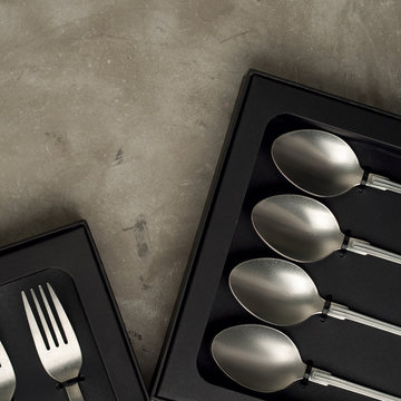 Top view of silver collection of knives forks spoons tablespoons and teaspoons in a black box on a gray concrete background