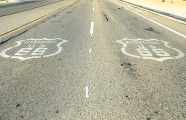 Fototapeta premium Pavement street sign on historic route 66 in Barstow, Mojave desert. Mother Road or Sixty Six background. Route 66 highway with sign on asphalt.