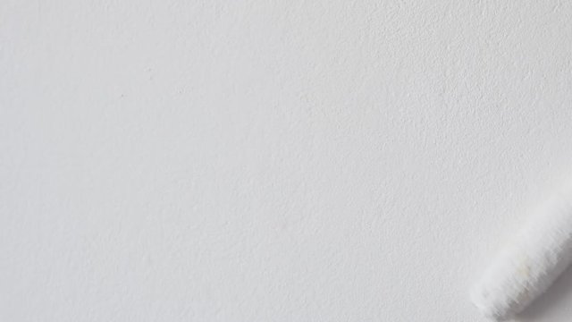 Slow motion white paint spreading on wall surface with roller