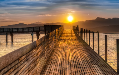 Obraz premium Dramatic sunrise during the Fall Equinox over the historical holzsteg pedestrian bridge crossinhg the Upper Zurich Lake (Obersee), part of the old Way of Saint James, Switzerland