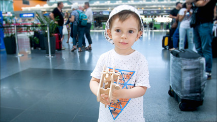 Portrait of cute smiling toddler boy with toy wooden airplane