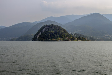 A landscape of Lake Como with the misty alpine hills in the distance. Lombardy, northern Italy.
