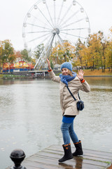Cheerful young woman dances near a lake in the park