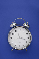 Top view of a classic alarm clock on dark blue background with copy space