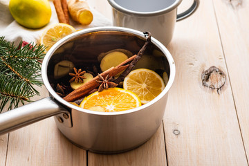 Mulled wine hot drink with citrus, apple and spices in aluminum casserole and Fir branch on background.