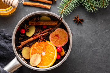 Fototapeta premium Mulled wine hot drink with citrus, apple and spices in aluminum casserole and Fir branch on background.
