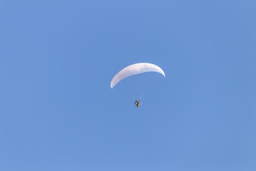 Paraglider flying with a paramotor over clear blue sky